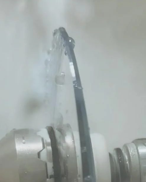 Máquina do laboratório da Dimel Óptica trabalhando uma lente, com jato de água